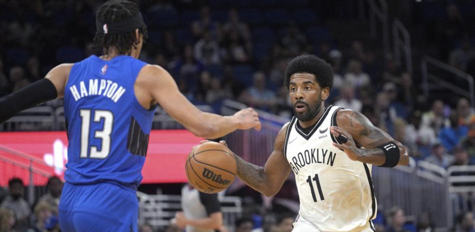 El escolta de los Nets de Brooklyn, Kyrie Irving (11), conduce frente al escolta de los Magic de Orlando, RJ Hampton (13), durante la primera mitad de un partido de baloncesto de la NBA el martes 15 de marzo de 2022 en Orlando, Florida.