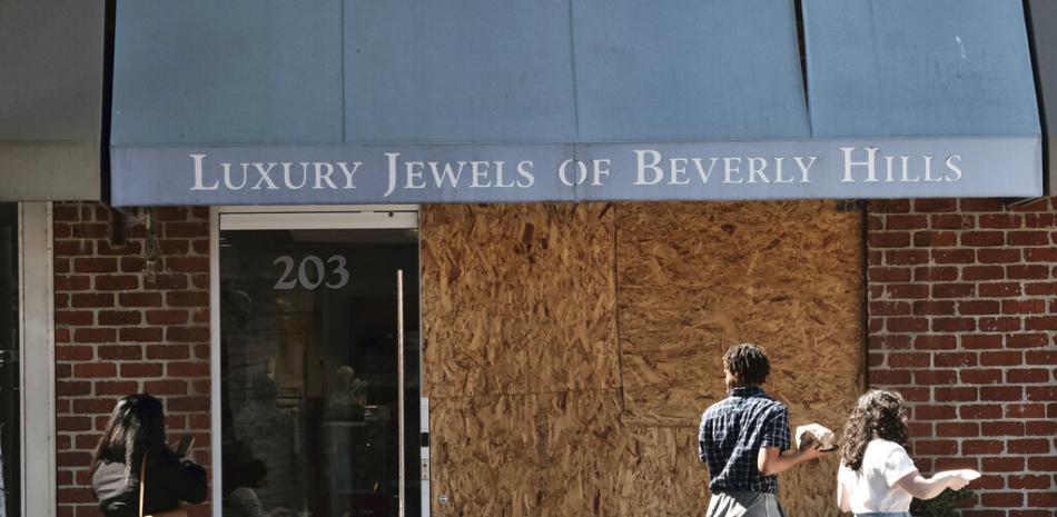 Transeúntes pasan frente a la tienda tapiada de Luxury Jewels en Beverly Hills, California, el miércoles 23 de marzo de 2022.

Foto: AP/Richard Vogel