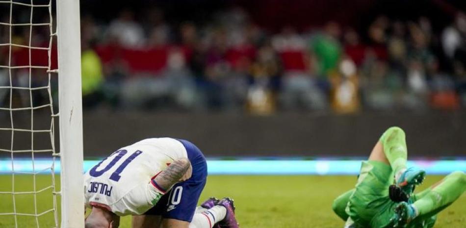 Christian Pulisic, de Estados Unidos, y Guillermo Ochoa, de México, se lamentan tendidos en la cancha durante el partido de la eliminatoria mundialista.