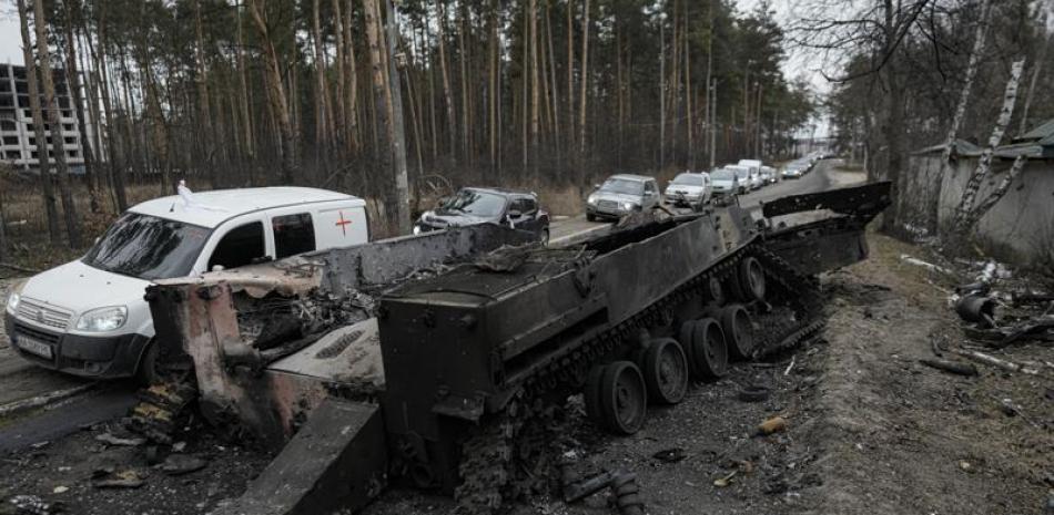 Una fila de vehículos pasa junto a un tanque ruso destruido, en Irpin, Ucrania, el 9 de marzo de 2022. (AP Foto/Vadim Ghirda, File)