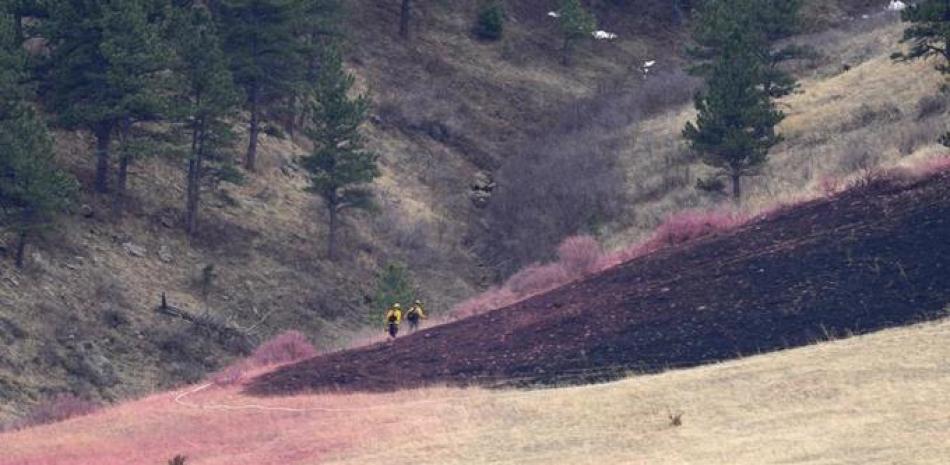 Dos bomberos avanzan junto a un área quemada por un incendio forestal, el domingo 27 de marzo de 2022, en Boulder, Colorado. (AP Foto/David Zalubowski)