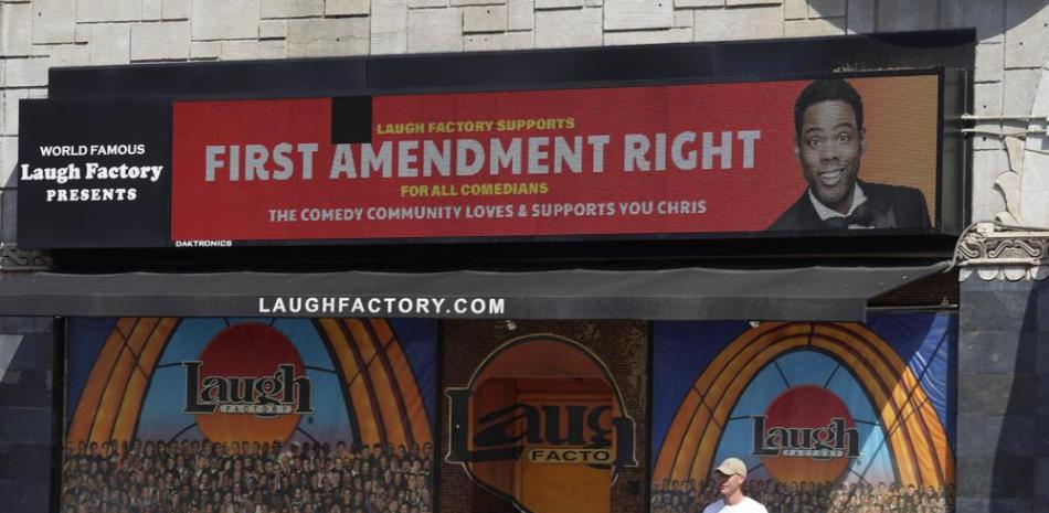 Un hombre parado bajo un mensaje de apoyo al comediante Chris Rock en la marquesina digital del club de comedia Laugh Factory, en Los Ángeles, el miércoles 30 de marzo de 2022. (Foto AP/Chris Pizzello),