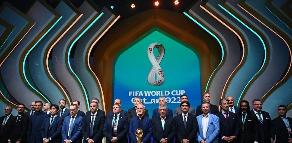 Parte de los entrenadores de diferentes países posan junto a la Copa Mundial de fútbol que será disputada a finales de este año en Catar.