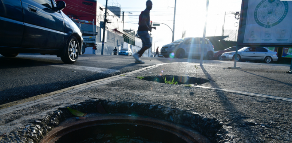 Peatones y vehículos enfrentan cada día el riesgo de caer en los agujeros por la falta de tapas y parrillas en las vías públicas. JORGE CRUZ /LISTÍN DIARIO