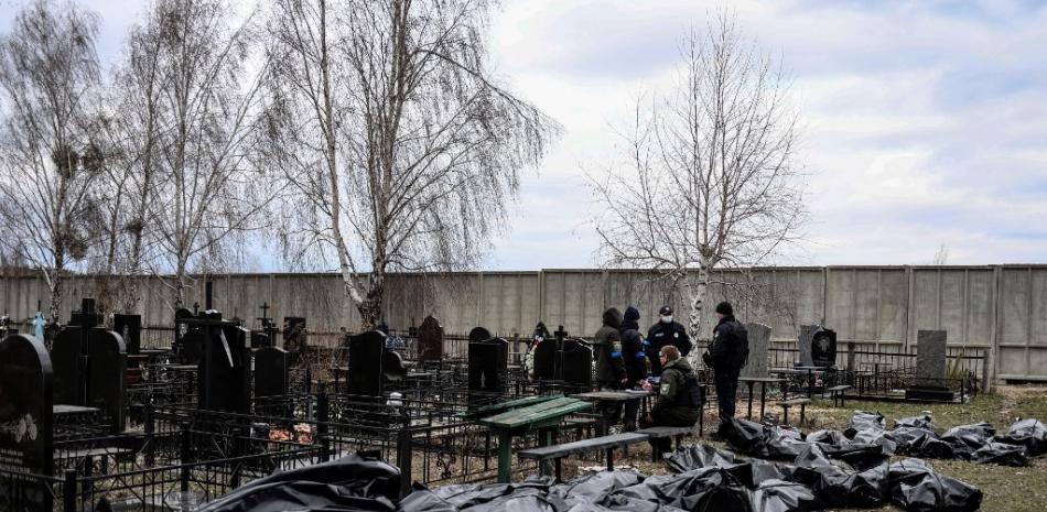 Bolsas de cadáveres son alineadas para su identificación por personal forense y oficiales de policía en el cementerio de Bucha, al norte de Kyiv, el 6 de abril de 2022, después de que cientos de civiles fueran encontrados muertos en las zonas de las que las tropas rusas se han retirado alrededor de la capital de Ucrania. Foto: Ronaldo Schemidt/AFP.