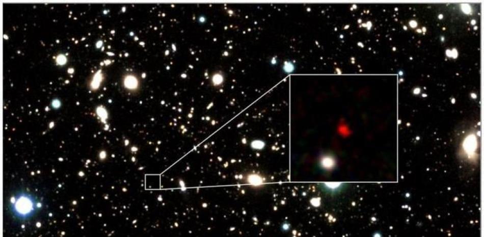 Esta imagen publicada el 8 de abril de 2022 muestra la galaxia más lejana HD1 (13,500 millones de años luz), el punto que aparece en rojo en el centro de una foto ampliada, según la revista Astrophysical. Fuente: AFP.