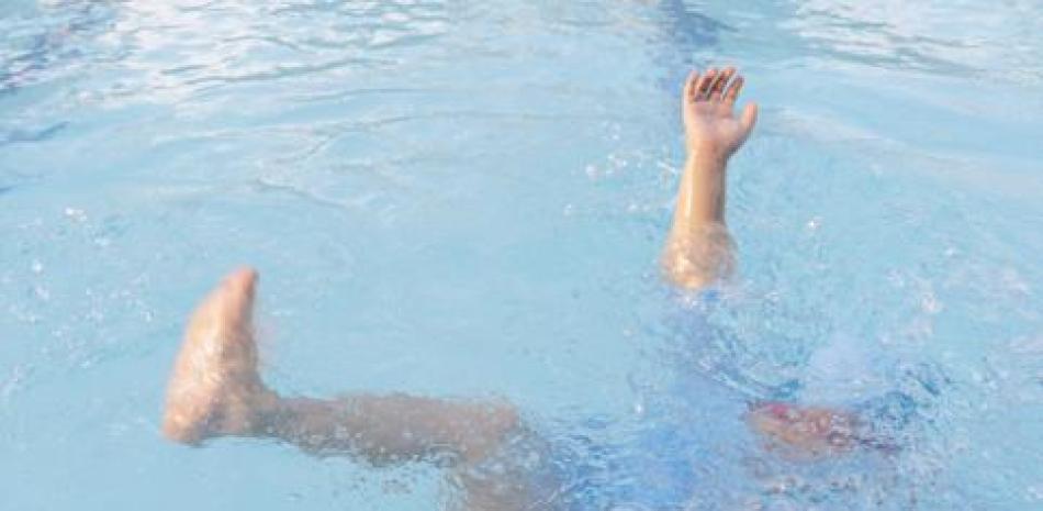 Persona ahogándose en una piscina. Foto de archivo.
