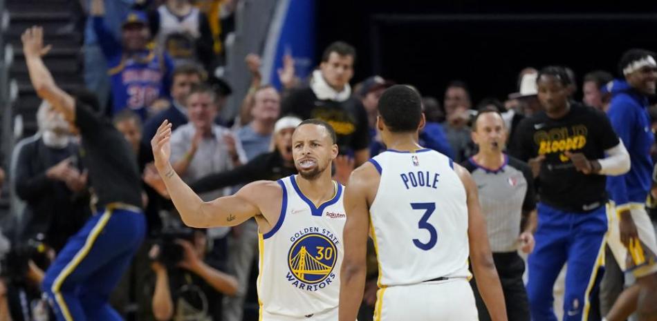 Stephen Curry (30), de los Warriors de Golden State, recibe la felicitación de su compañero Jordan Poole (3) tras anotar contra los Nuggets de Denver.