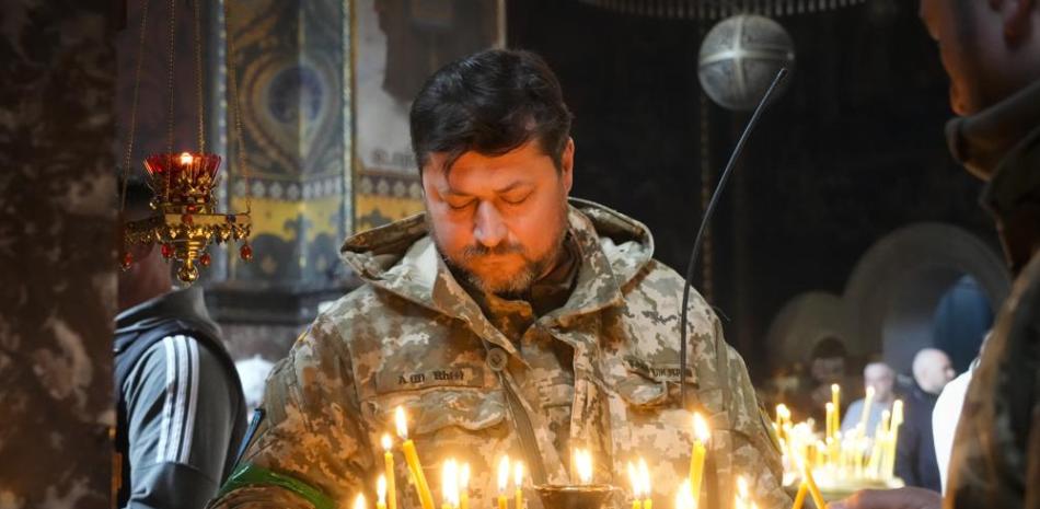 Un soldado ucraniano enciende velas en la Catedral Volodymysky durante la celebración de la Pascua en Kiev, Ucrania, el domingo 24 de abril de 2022. (Foto AP/Efrem Lukatsky)