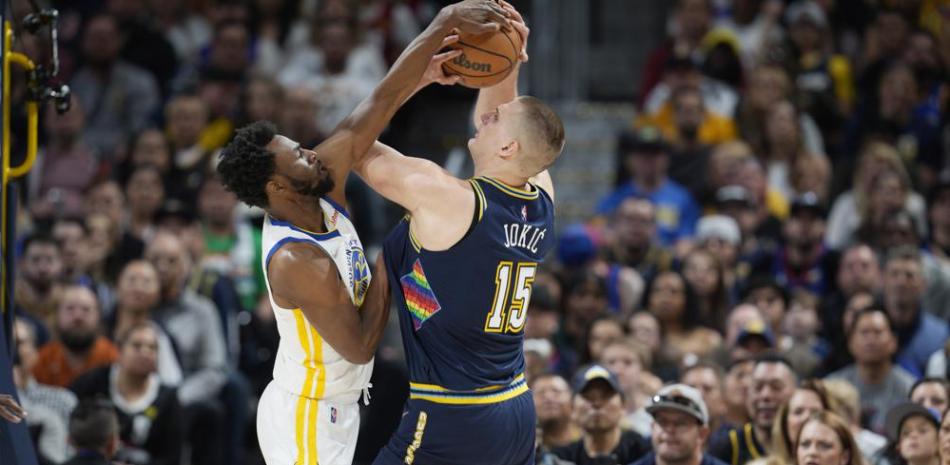 Andrew Wiggins, izquierda, de los Warriors de Golden State, bloquea un tiro de Nikola Jokic, de los Nuggets de Denver, en la primera mitad del cuarto partido de la serie de la primera ronda de los playoffs de la NBA, el domingo 24 de abril de 2022, en Denver.