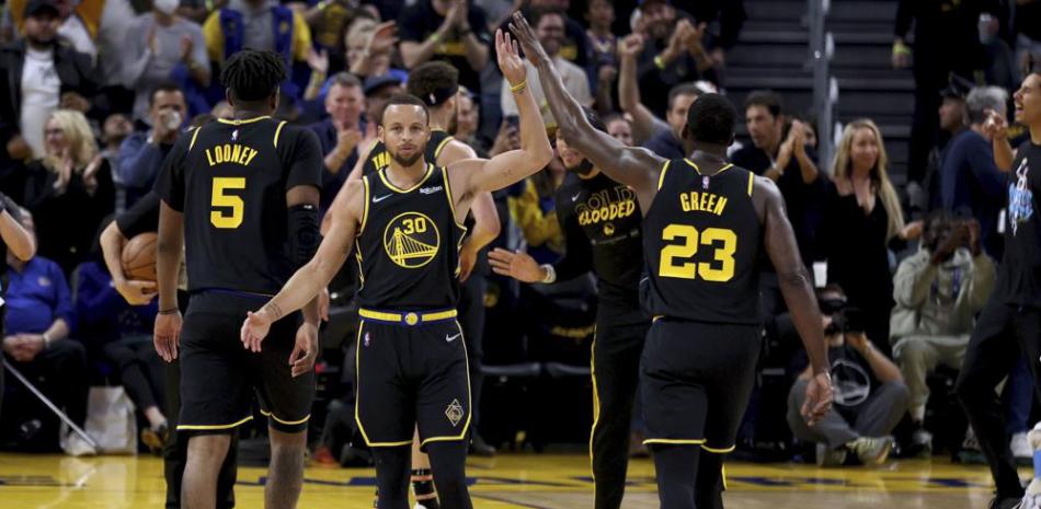 El jugador de los Warriors State Stephen Curry (30) recibe la felicitación de Draymond Green en la primera mitad del quinto juego de la serie de primera ronda frente a Denver.