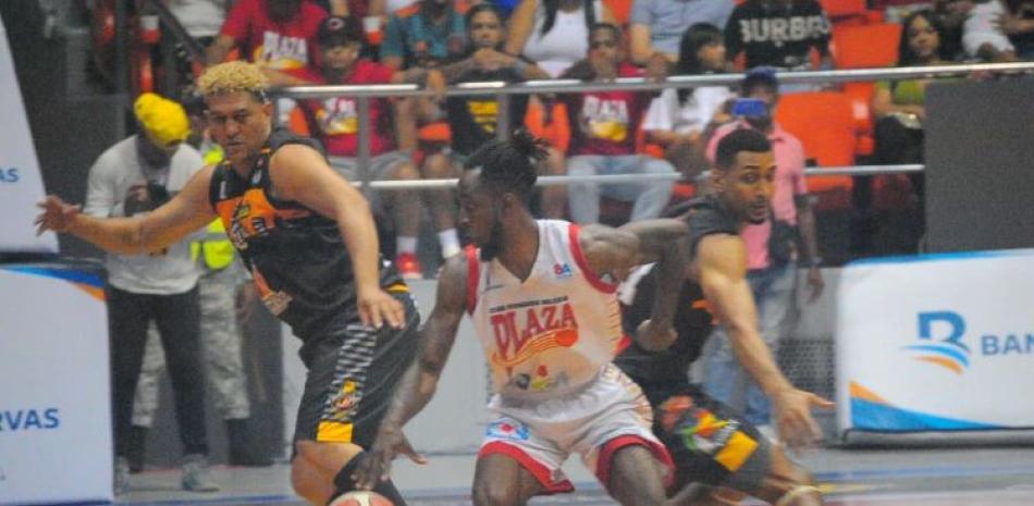 Devin Brooks, del Plaza Valerio, burla la defensa de Adris Rodríguez y Gelvis Solano, del GUG, en el quinto partido de la serie final del baloncesto superior de Santiago.