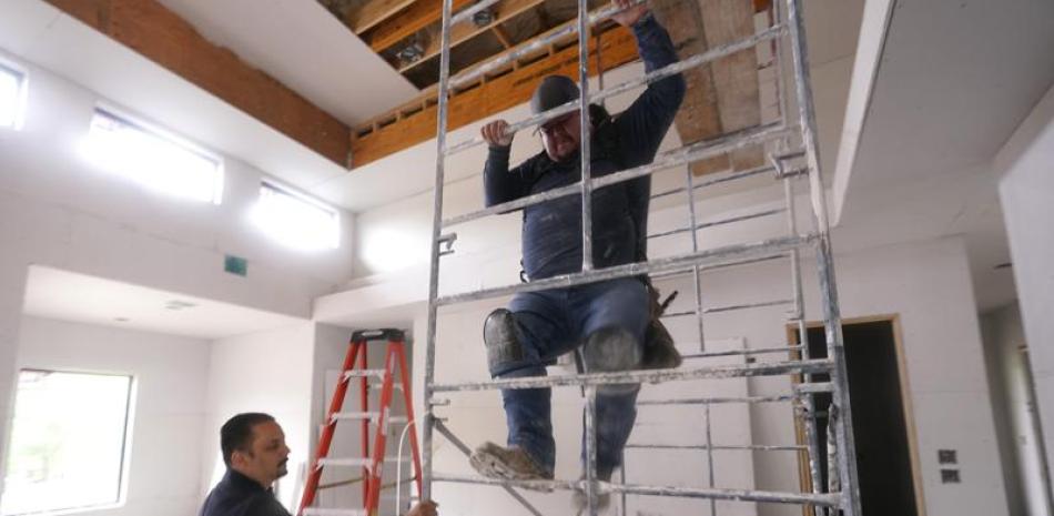Joshua Correa, izquierda, afirma un andamio para un trabajador en una casa en construcción en Plano, Texas, 3 de mayo de 2022. Hay unos 2 millones de inmigrantes menos de lo previsto en Estados Unidos, lo cual contribuye a la escasez y el aumento de precios. (AP Foto/LM Otero)