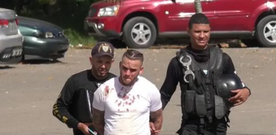 Richard Báez cuando era conducido ensangrentado luego de su detención por policías.