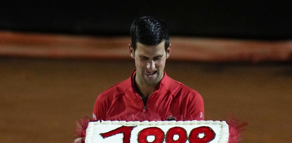 El serbio Novak Djokovic sostiene un pastel adornado con el número 1.000, tras llegar a esa cifra de triunfos en su carrera el sábado 14 de mayo de 2022, en el Abierto de Italia (AP Foto/Alessandra Tarantino)