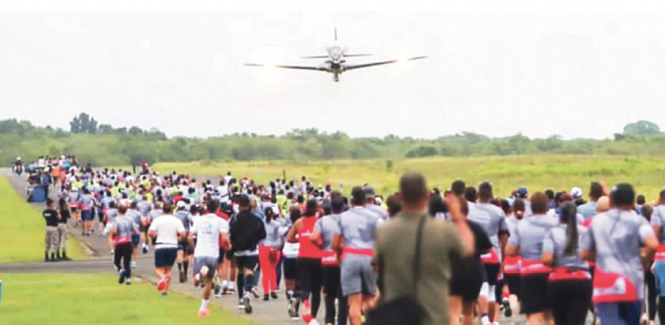 Un grupo de maratonistas observa el vuelo de una avioneta mientras competían en la Base Áerea de San Isidro.