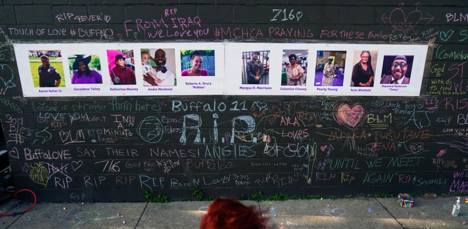 Foto del 19 de mayo de 2022 de una persona visitando un monumento improvisado cerca del sitio de una masacre en un supermercado en Buffalo la semana previa. (AP Foto/Matt Rourke)