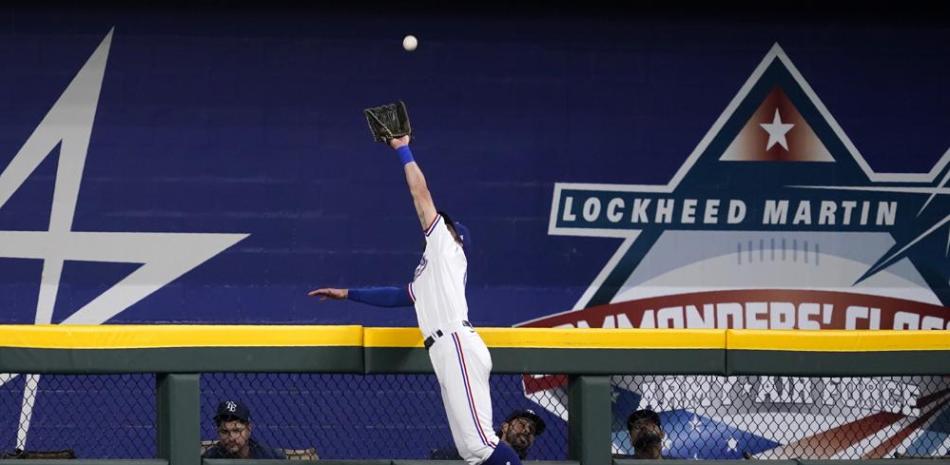 El jardinero central de Texas Eli White salta sobre el muro para atrapar un batazo de Ji-Man Choi, de los Rays de Tampa Bay, en el primer inning del juego de la MLB.