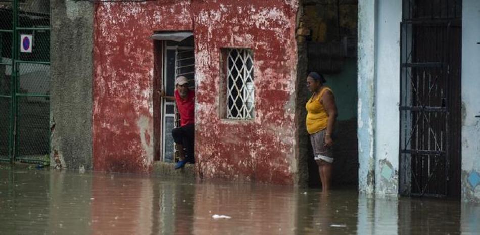 Personas miran una calle inundada desde una casa de La Habana, el 3 de junio de 2022. Los remanentes del huracán Agatha provocan este viernes intensas y persistentes lluvias en las provincias occidentales y centrales de Cuba.
YAMIL LAGE / AFP