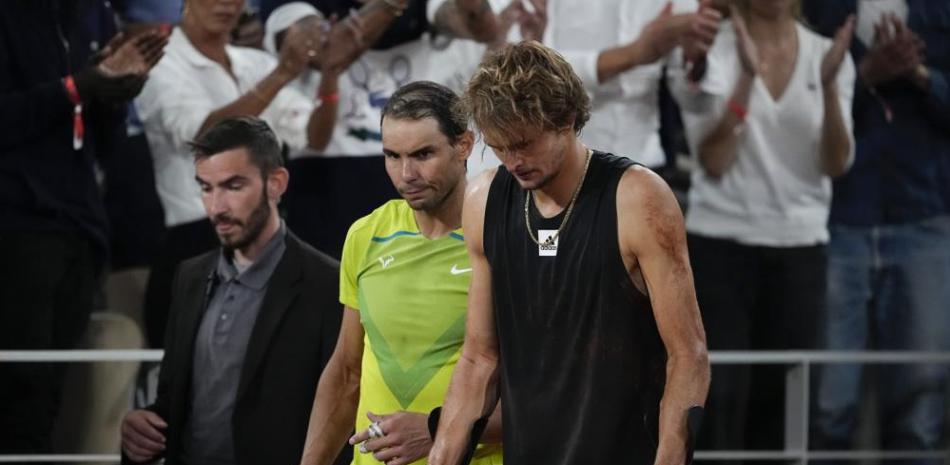 El español Rafael Nadal, centro, camina al lado del alemán Alexander Zverev, derecha, quien avanza en muletas luego de sufrir una lesión de tobillo derecho.
