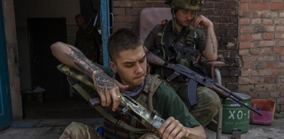 Un miembro de seguridad de un equipo de rescate médico limpia su arma en la región de Donetsk, en el este de Ucrania, el sábado 4 de junio de 2022. (AP Foto/Bernat Armangue)