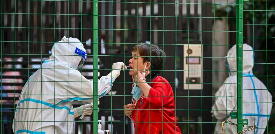 Un trabajador de la salud toma una muestra de hisopo de una mujer en la entrada de un área residencial bajo encierro de Covid-19 en el distrito de Xuhui de Shanghai el 8 de junio de 2022.
Foto: Héctor Retamal| AFP