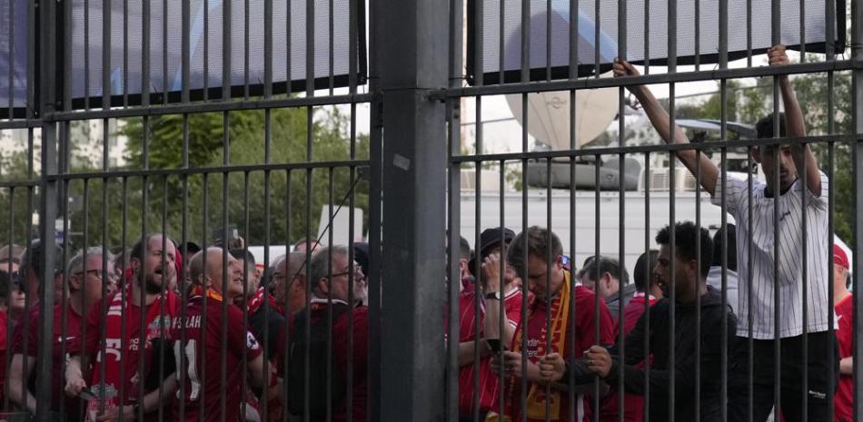 Un aficionado trata de subir una valla metálica frente al Stade de France antes de la final de la Liga de Campeones entre Liverpool y Real Madrid, en Saint Denis.