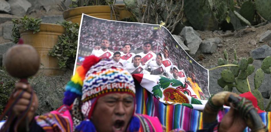 Un chamán peruano realiza un ritual de buena suerte frente a un foto de la selección peruana de fútbol, en el cerro de San Cristóbal en Lima.. (AP)