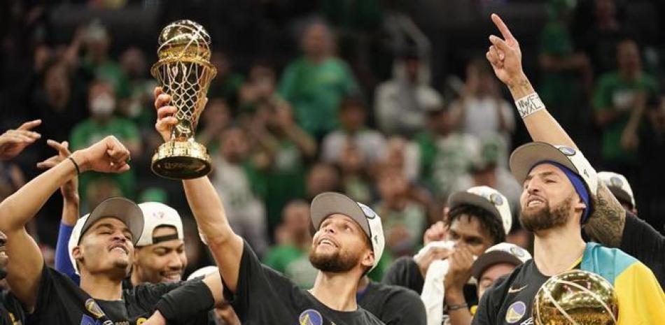 El escolta de los Golden State Warriors, Stephen Curry, en el centro, sostiene el Trofeo Bill Russell al jugador más valioso después de que los Warriors derrotaron a los Boston Celtics en el Juego 6 para ganar el campeonato de las Finales de la NBA de baloncesto, el jueves.