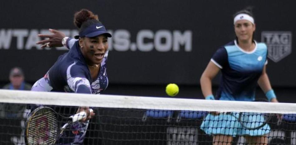 Serena Williams devuelve ante la mirada de Ons Jabeur durante un partido de dobles en el torneo de Eastbourne.