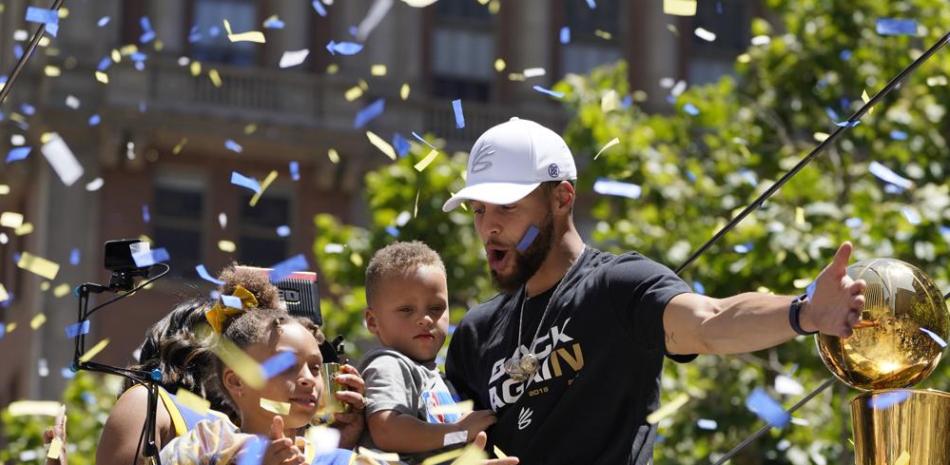 Stephen Curry saluda en medio del confeti azul y dorado, mientras recorre las calles de San Francisco en el desfile de celebración del campeonato de la NBA.
