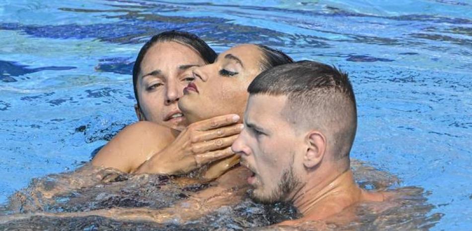 Anita Alvarez, centro, es sacada de la piscina por la entrenadora Andrea Fuentes, izquierda, y un miembro del torneo, al perder el conocimiento durante su rutina.