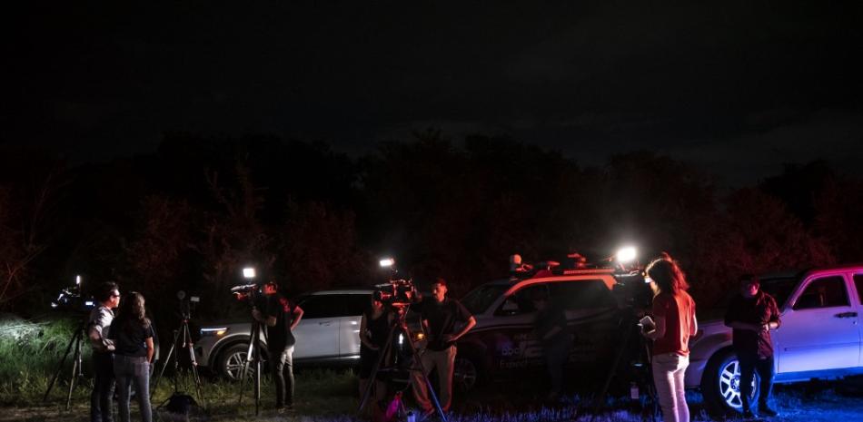 Reporteros de noticias cerca de la escena donde se descubrió un tractor-remolque con migrantes dentro en las afueras de San Antonio, Texas, el 27 de junio de 2022. Foto: Sergio Flores/AFP.