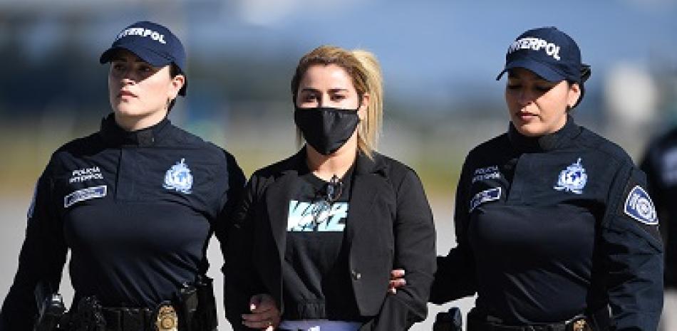 Nini Johana Usuga, hermana del narcotraficante Dairo Antonio Usuga, alias Otoniel, es escoltada por policías de Interpol antes de ser extraditada a EE. UU. en el Aeropuerto Internacional El Dorado, en Bogotá, Colombia. Foto: AFP Forum