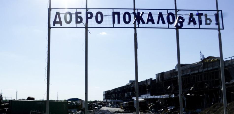 Un cartel con la leyenda "¡Bienvenidos!" aparece frente a un edificio destruido en la ciudad de Mariupol el 1 de julio de 2022, en medio de la actual acción militar rusa en Ucrania. Foto: AFP.