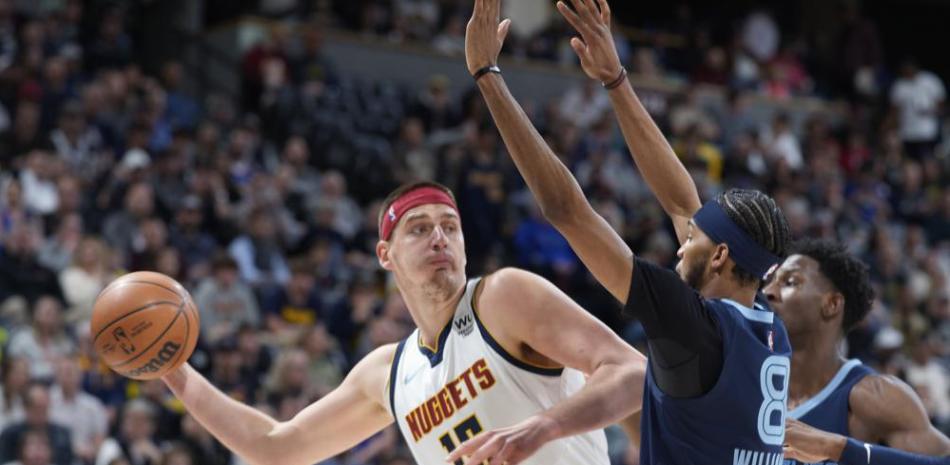 El pívot de los Nuggets de Denver Nikola Jokic intenta pasar el balón superando al base de los Grizzlies de Memphis Ziaire Williams.