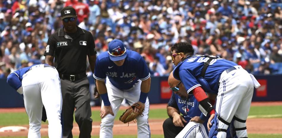 Kevin Gausman, de los Azulejos, es examinado tras ser golpeado por una pelota bateada por un jugador de los Rays de Tampa Bay en el segundo inning.