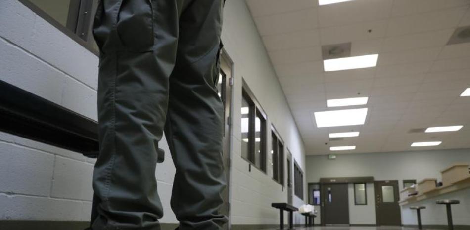 ARCHIVO - En imagen de archivo del 28 de agosto de 2019, un guardia de seguridad se encuentra en el área de admisión del Centro de Procesamiento del ICE en Adelanto, California. (AP Foto/Chris Carlson, archivo)