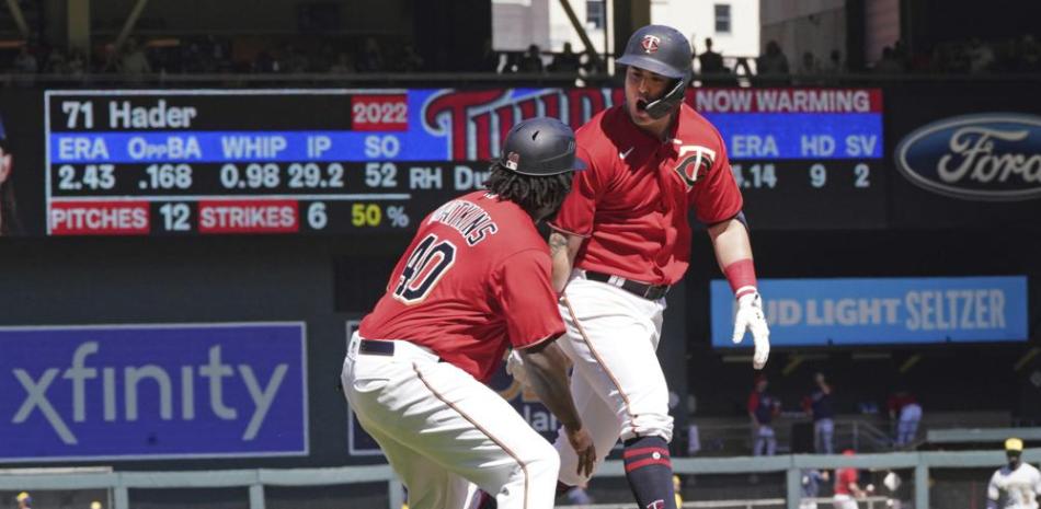 José Miranda (derecha) de los Mellizos es saludado por el coach de tercera base Tommy Watkins tras batear un jonrón de tres carreras ante Josh Hader de Milwaukee.