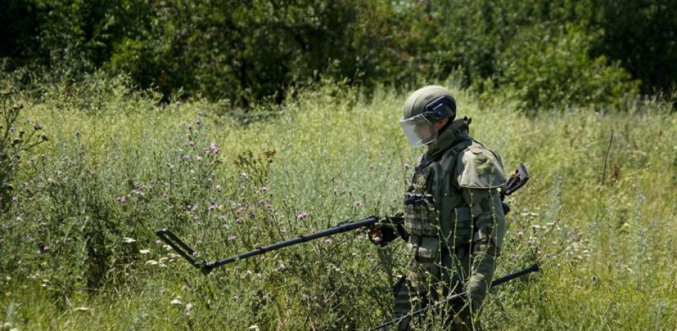Un experto ruso en remoción de minas trabaja para encontrar y desactivar minas a lo largo de la línea de alto voltaje en Mariúpol, en el este de Ucrania, el miércoles 13 de julio de 2022. Esta foto fue tomada durante una viaje organizado por el Ministerio de Defensa ruso. (Foto AP)