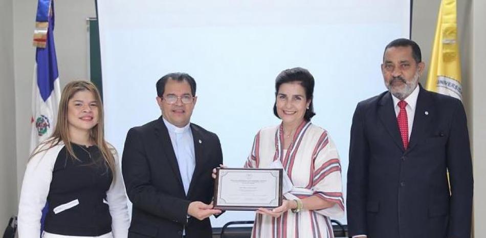 El padre Secilio Espinal entrega una placa de reconocimiento a la doctora María Amalia León. Les acompañan, Mariano Rodríguez e Ibeth Guzmán.