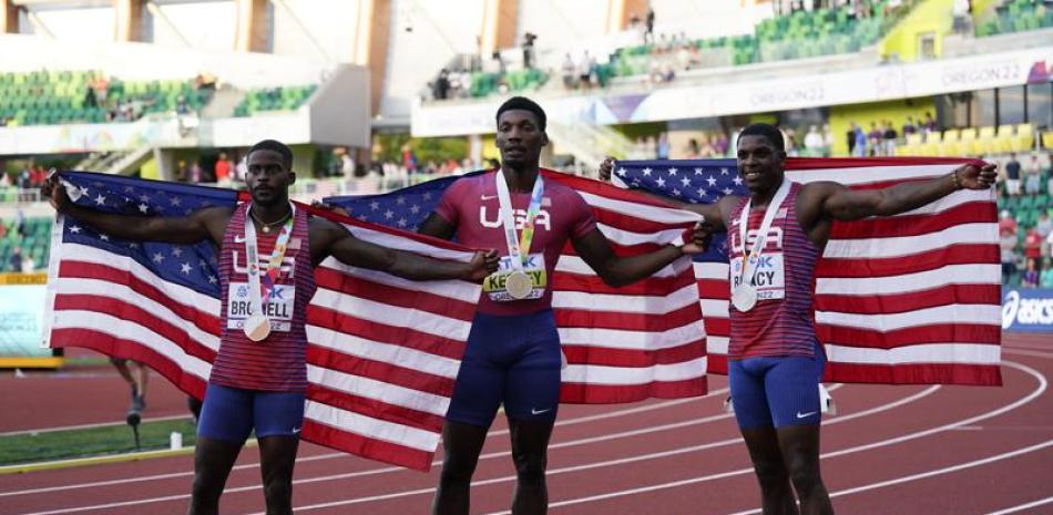 Fred Kerley, al centro, junto a sus compañeros Marvin Bracy y Trayvon Bromell se cubren con la bandera de Estados Unidos.