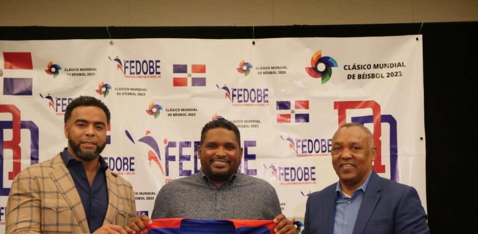 Rodney Linares exhibe la camiseta número 23 que usará tras su designación como dirigente del equipo dominicano que estará en el Clásico Mundial. A Sus extremos Juan Núñez Nepomuceno y Nelson Cruz.
