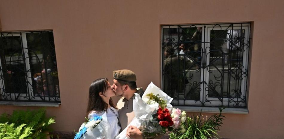 El militar ucraniano Vitaliy, de 25 años, besa a su esposa frente a una de las oficinas de registro de la ciudad justo después de la ceremonia de boda en Kiev el 23 de julio de 2022. SERGEI SUPINSKY / AFP