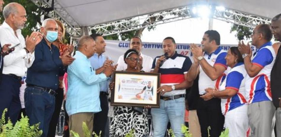 Hansel Salvador, recibe placa de reconocimiento en representación de su hijo, Hansel Emmanuel por parte del Comité Organizador de los Juegos Deportivos.