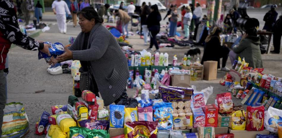 Una vendedora completa una transacción en un mercado donde la gente puede comprar o intercambiar bienes, en las afueras de Buenos Aires, Argentina, el miércoles 10 de agosto de 2022. AP Foto/Natacha Pisarenko