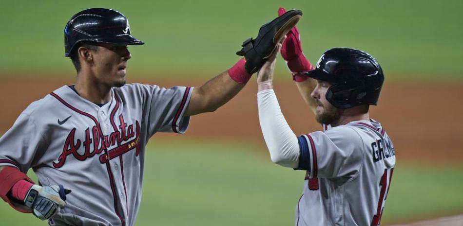 Vaughn Grissom y Robbie Grossman de los Bravos de Atlanta se felicitan tras el doble de Chadwick Tromp en la cuarta entrada del encuentro ante los Marlins de Miami.