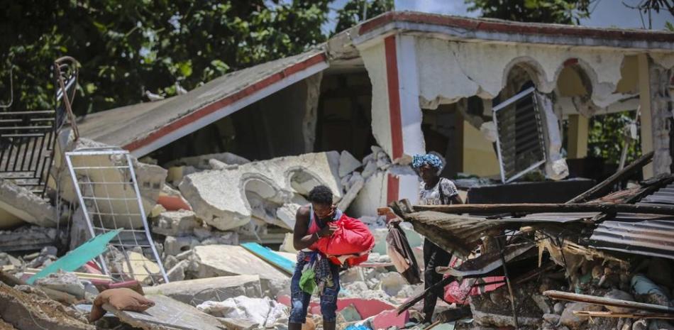 Unas mujeres recuperan sus pertenencias de sus casas destrozadas el domingo 15 de agosto de 2021, en Los Cayos, Haití, luego del terremoto de magnitud 7.2. AP