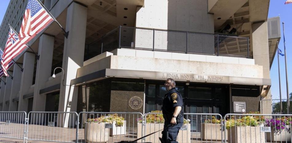 Un oficial de policía de la Oficina Federal de Investigaciones camina con su perro de trabajo frente a la sede del FBI en Washington, el sábado 13 de agosto de 2022. Ap