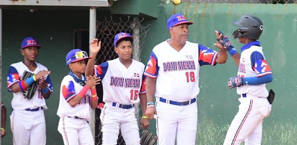 Ramón Genao, dirigente del equipo dominicano felicita a uno de los jóvenes del plantel quisqueyano al anotar una de las carreras.